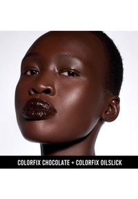 Mørk hud med glinsende læber, der viser en dyb chokoladefarve, glat tekstur og bløde højdepunkter. Nærbillede af ansigtstræk mod en hvid baggrund.