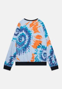 Sweatshirt tie-dye coloré avec des tourbillons de bleu, orange et violet, sur un fond texturé bleu clair, et des poignets et un ourlet côtelés noirs.