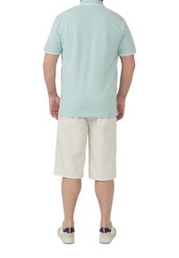 Hellblaues Polohemd mit weißem Kragen, kombiniert mit cremefarbenen Shorts. Von hinten angezeigt, ohne sichtbare Logos oder ausgeprägte Muster.