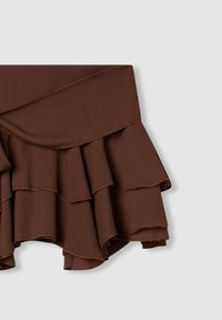 Gonna marrone arricciata con più balze, caratterizzata da una texture liscia e cuciture a contrasto ai margini.