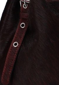 Donkerbruin leren band met zilveren hardware, voorzien van vijf oogjes en een zachte, gestructureerde oppervlakte. Over het geheel heeft het een verfijnde uitstraling.