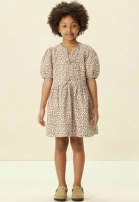 Leopardenmusterkleid mit Puffärmeln, rundem Ausschnitt und geraffter Taille. Weicher Stoff in hellem Beige mit braunen Punkten.