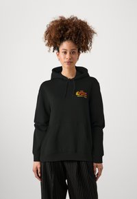 Zwarte hooded sweatshirt met een voorkant zak, voorzien van kleurrijke tekst op de borst. Gemaakt van zachte stof, heeft ribgebreide manchetten en zoom.