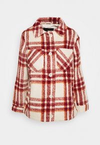 Flanellskjorta jacka med röd och orange rutmönster på en krämfärgad bakgrund. Har krage, knappar och bröstficka. Mjuk textur.