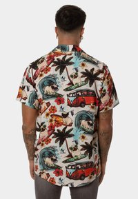 Camisa de manga corta de algodón con un estampado tropical que presenta tablas de surf, palmeras y furgonetas vintage en colores vibrantes.