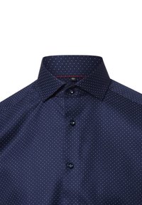 Camicia blu navy con colletto a punta, caratterizzata da piccoli pois bianchi e chiusura con bottoni. Tessuto liscio con una leggera lucentezza.