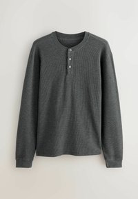 Maglietta henley grigia a maniche lunghe realizzata in un tessuto testurizzato, con scollo a girocollo e patta con tre bottoni. Nessun motivo visibile.