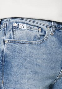 Ljusblå denimjeans med en klassisk design med fem fickor, synlig sömnad och en CK-logotag ovanför bakfickan.
