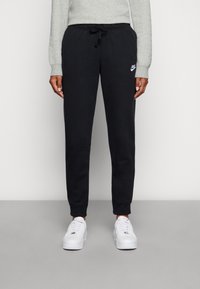 Pantaloni della tuta neri con vita elasticizzata e coulisse, con un logo Nike bianco sul lato. Materiale morbido in misto cotone.