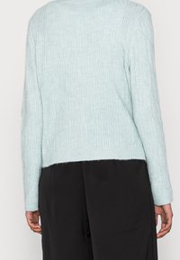 Maglione a coste blu chiaro, con maniche lunghe e orlo cropped. Il motivo testurizzato presenta linee verticali ed elementi a zigzag sottili.