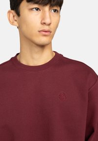 Bourgondische sweatshirt met een ronde hals, met een textuur stof, een subtiel geborduurd logo op de borst en geribbelde manchetten.
