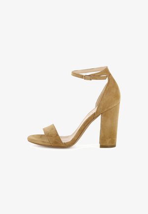 Tan suède sandalen met open teen, hoge hak, enkelriem en blokhak, zijaanzicht op witte achtergrond.