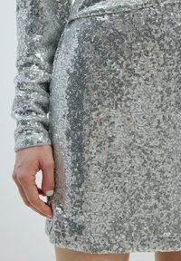 Silberner Pailletten-Kleid mit taillierter Passform. Verfügt über unterschiedlich große Pailletten auf einem durchsichtigen Untergrund, voluminöse Ärmel und einem Saum mit einem leichten Ausschlag.