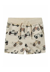 Shorts beige avec un motif répété de véhicules et de motos. Taille élastique avec cordon de serrage et poches latérales. Texture de tissu douce.