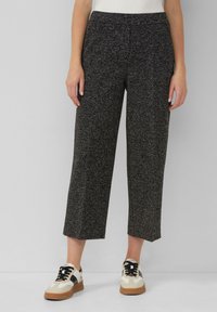 Gestructureerde zwart-witte cropped broeken met een elastische tailleband, gecombineerd met crèmekleurige en zwarte sneakers met een gumrubberen zool.