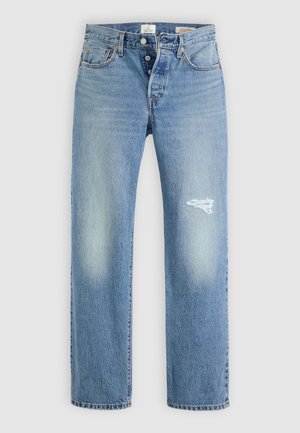 Jeans de mezclilla azul claro con un corte relajado, que presentan un parche desgastado en el muslo derecho, cinco bolsillos y cierre con botón de metal.