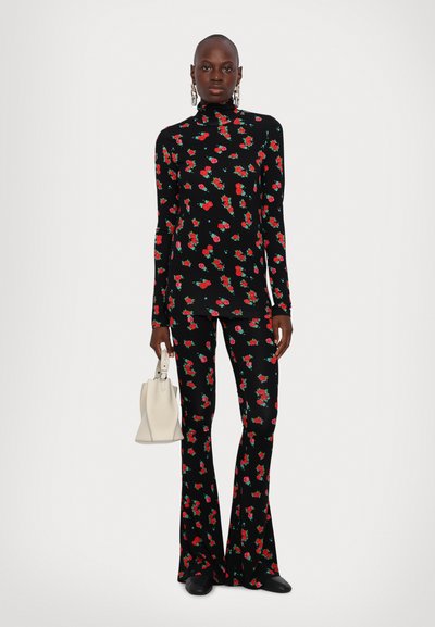 Tenue florale noire comprenant un col roulé à manches longues et un pantalon évasé, décorée de motifs de roses rouges et vertes. Inclut un sac à main blanc.