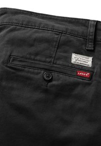 Pantaloni in twill neri con una tasca posteriore con bottone, un'etichetta bianca con la scritta "Levi Strauss & Co." e un'etichetta rossa "Levi's".