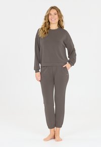 Ensemble de loungewear gris en tissu doux. Comprend un haut à manches longues à col rond et un pantalon élastique assorti avec des poches latérales.