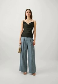 Μαύρο σατέν τοπ με λαιμόκοψη sweetheart, συνδυασμένο με φαρδύ παντελόνι από ανοιχτό μπλε τζιν. Τα αξεσουάρ περιλαμβάνουν μία μπεζ τσάντα.