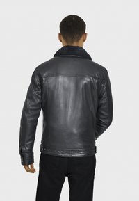 Pánska čierna kožená bunda so ovčím golierom, priliehavý strih, hladká textúra a zapínacie manžety, zobrazená zozadu.