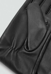 Guantes de cuero negro con un acabado texturizado, que presentan detalles fruncidos y una zona de dedos suave. El diseño es elegante y ajustado.