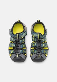 Infradito sportivi con design grigio e giallo, tomaia in rete, cinturini regolabili e suole in gomma. Soletta testurizzata per il comfort.
