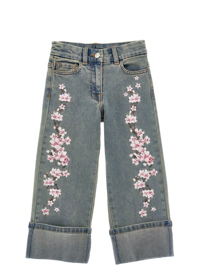 Jeans in denim azzurro chiaro con un design di fiori di ciliegio rosa ricamati lungo i lati e orli arrotolati.