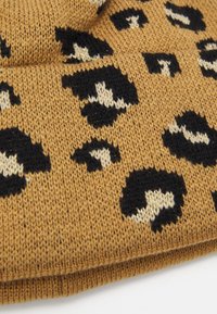Pletená čiapka v zlatej hnedej farbe s čierno-krémovým leopardím vzorom. Mäkka textura a skladaný lem pre dodatočné teplo.