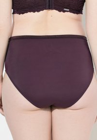 Hooggesneden slip in diep bordeauxkleurige stof, gladde textuur, zonder zichtbare naden, met een stevige tailleband en een ontwerp met volledige bedekking.