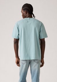 Lys blå bomulds-T-shirt med korte ærmer, afslappet pasform og rund hals, parret med lyse denimjeans. Ingen tydelige mønstre eller accenter synlige.