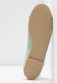 Semelle d'une ballerine vert menthe à fond en caoutchouc antidérapant embossé de petits motifs de chaussures de ballerine et du logo "Pretty Ballerinas".