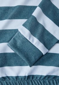 Tessuto a righe in turchese e bianco, con una maglia testurizzata e dettagli di polsini e vita elastica. Design morbido e casual per il massimo comfort.