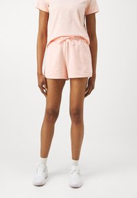 T-shirt de algodão rosa claro combinado com calções a condizer, com uma cintura elástica e cordão. Design simples, sem padrões ou detalhes visíveis.