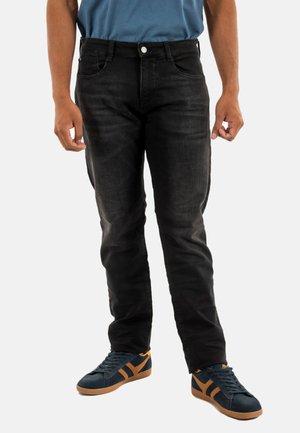 Zwarte denim jeans met een rechte pasvorm, vijf pockets en een subtiele vervaging. Gecombineerd met donkerblauwe sneakers met oranje strepen.
