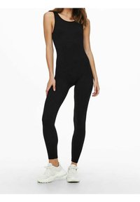 Mono atlético negro con un diseño ajustado, tirantes delgados y una textura suave, combinado con tenis blancos. Estilo simple y sin costuras.