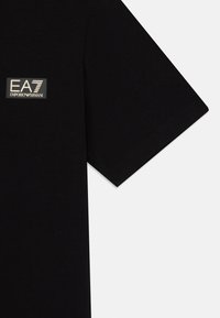 Fekete pamut póló, arany EA7 Emporio Armani logóval a mellkason, rövid ujjakkal, sima textúrával és klasszikus szabással.