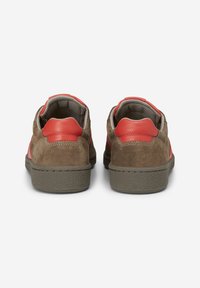 Scarpe in suede marrone con dettagli in pelle rossa, dotate di una suola in gomma texture e rivestimento in tessuto grigio. Design a profilo basso con un aspetto casual.