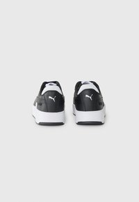 Black sneakers with white accents, textured leather material, and a rubber sole. Features a prominent logo on the heel and tongue.