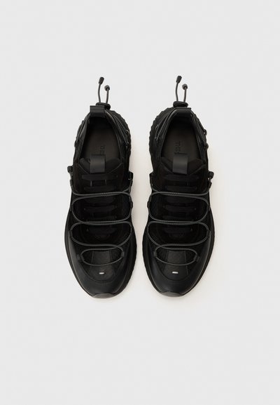Black sneakers featuring a mix of smooth and textured materials, elastic laces, padded collar, and a prominent, rugged sole.
