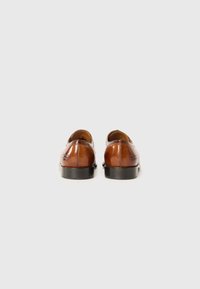 Chaussures en cuir marron avec une finition lisse, bout arrondi, petit talon noir et un minimum de détails de couture sur les côtés arrière.