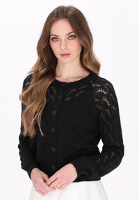 Cardigan nero lavorato a maglia con un motivo di pizzo testurizzato, caratterizzato da un collo rotondo e sei bottoni frontali. Maniche lunghe con polsini aderenti.