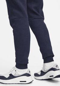 Meripikaat navy-huopa, joissa on ribbikujat, yhdistetty valkoisiin ja navy Nike Air Max -kenkiin, joissa on verkko- ja mokkamateriaaleja sekä näkyvä brändäys.