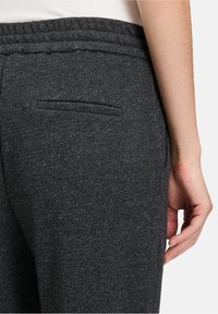 Dunkelgraue Joggerhose aus strukturiertem Stoff, mit elastischem Bund und kleinem Detail einer Gesäßtasche.