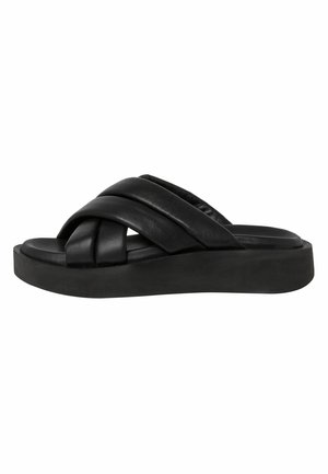 Sandales à glissière en cuir noir avec des lanières torsadées et une semelle épaisse. Texture lisse avec un design minimaliste.