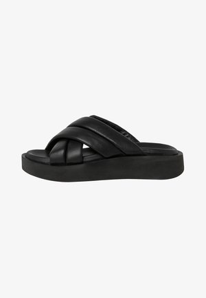 Sandales à glissière en cuir noir avec des lanières torsadées et une semelle épaisse. Texture lisse avec un design minimaliste.