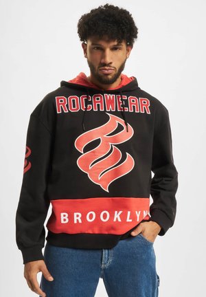 Svart og rød hettegenser med et grafisk logo, "ROCAWEAR" i fete bokstaver, med snor i hetten og en "BROOKLYN" stripe nederst.
