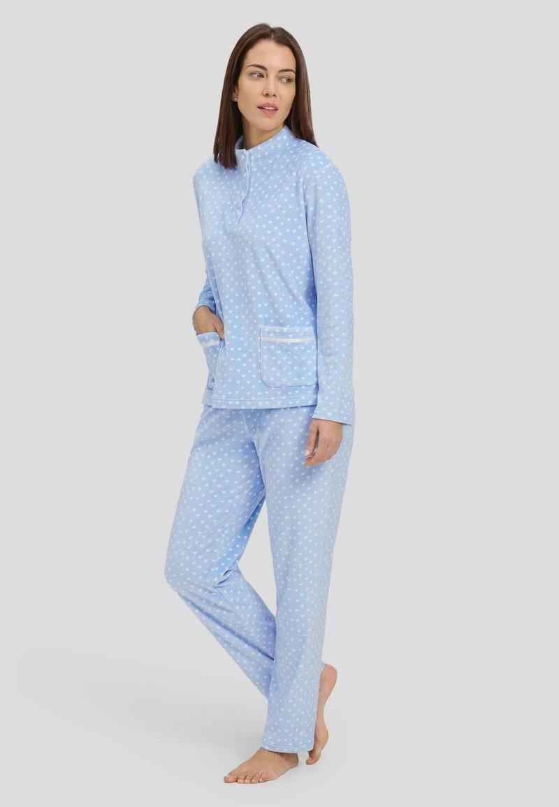 Conjunto de pijama azul claro que incluye una camiseta de manga larga con cuello alto y detalles de botones, y pantalones a juego con pequeños patrones de corazones blancos.