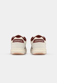 White and burgundy sneakers with a smooth leather and suede finish, featuring a low-top design and "Converse" branding on the heels.