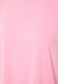 T-shirt rose clair à manches courtes et col rond sans motifs visibles ni dessins sur un fond uni.